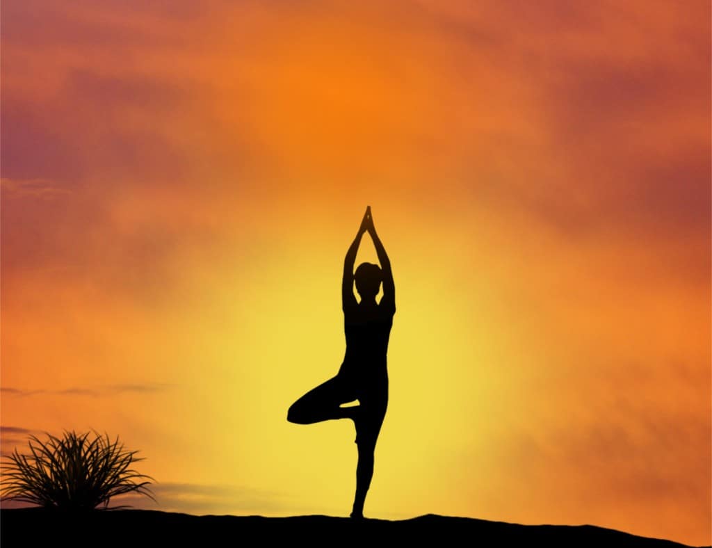 woman doing yoga in a beautiful orange sunset