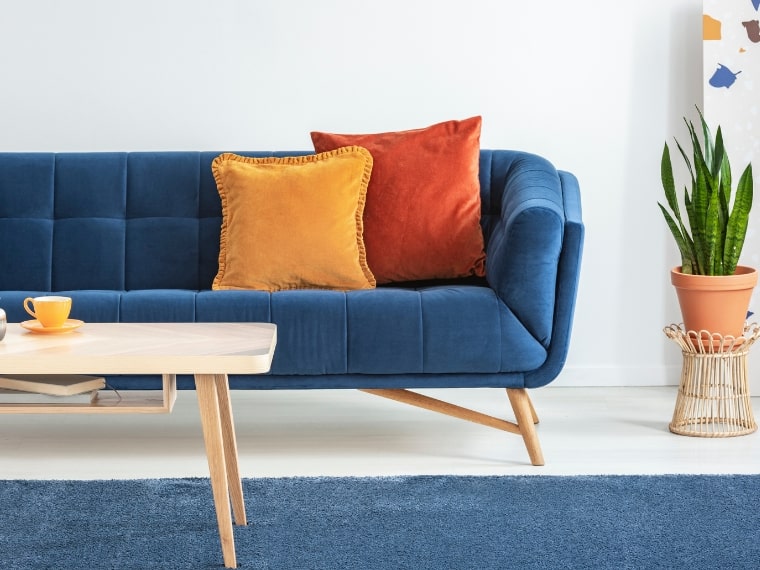 orange and red cushions on a luxurious royal blue sofa