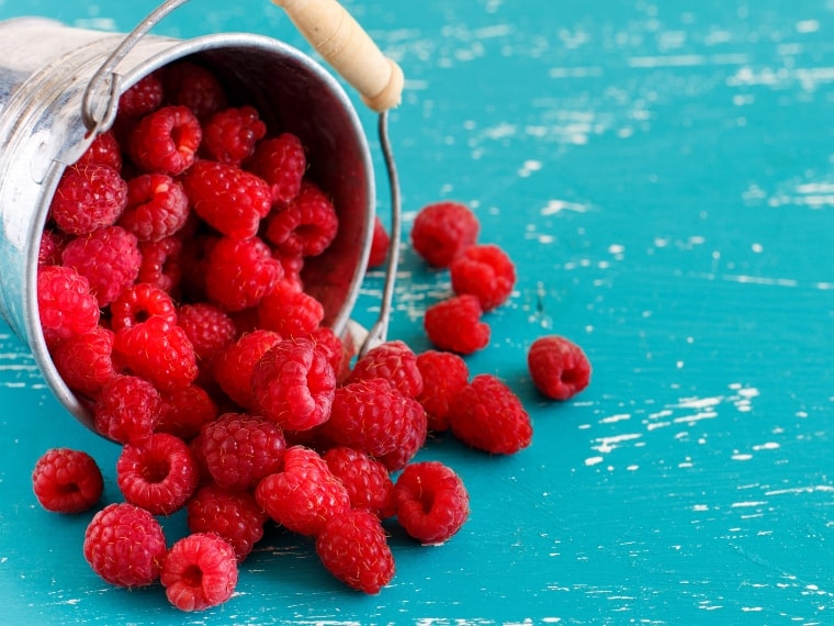 Fresh Raspberries Whirling on a Turquoise Background