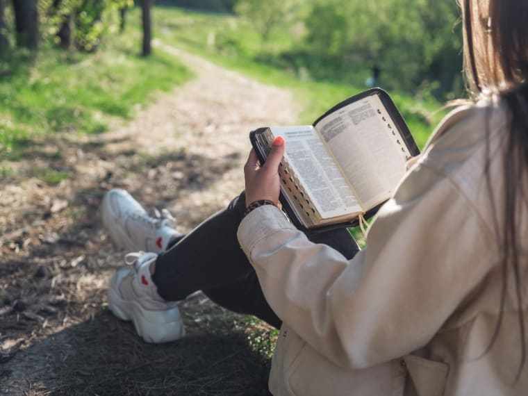 Girl reading the Bible in nature