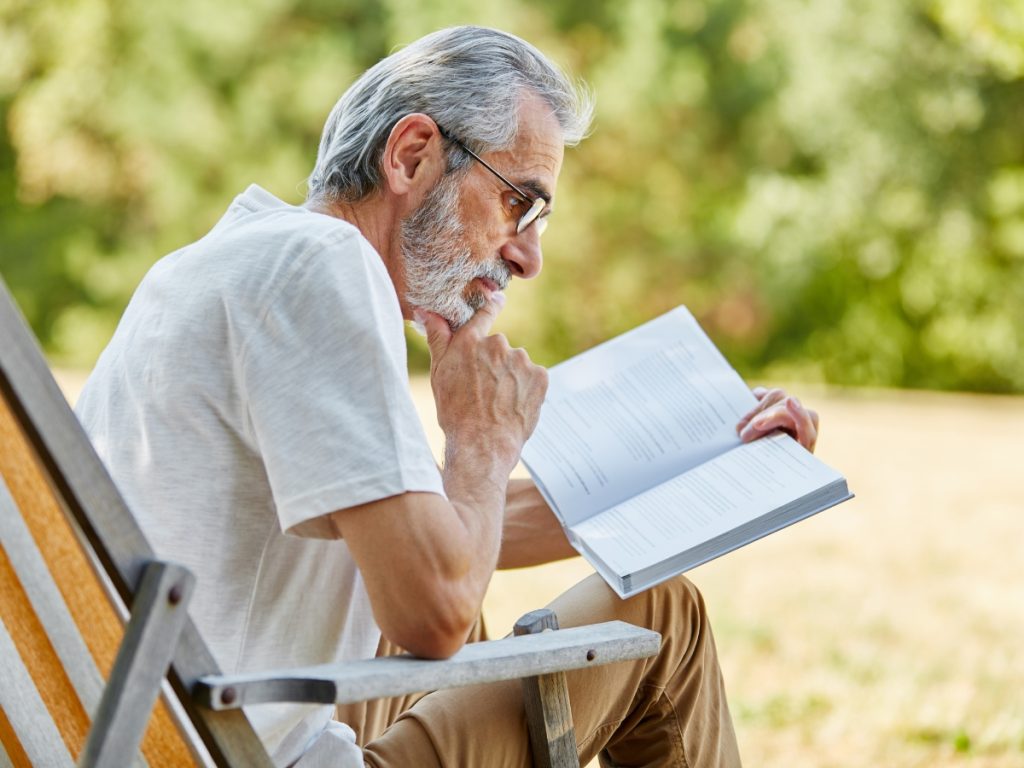 Old man with gray hair reading a book